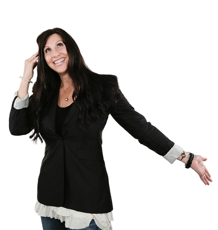 A smiling woman in a black blazer, playfully gesturing with one hand while looking upwards, showcasing confidence and joy.